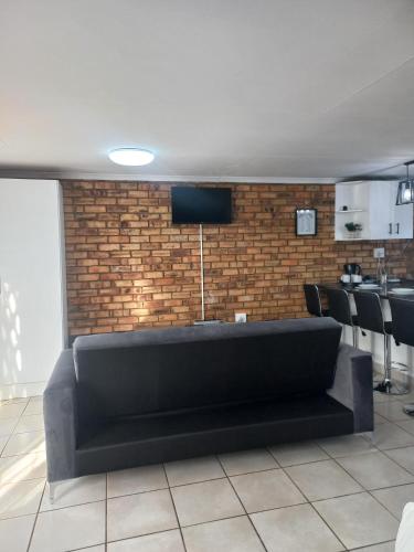 a black couch in a room with a brick wall at Inni Bush Guesthouse in Noordheuwel