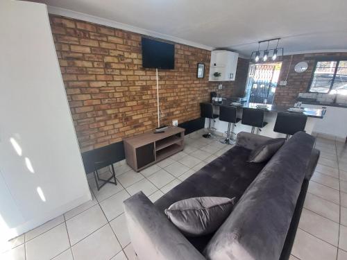 a living room with a couch and a brick wall at Inni Bush Guesthouse in Noordheuwel