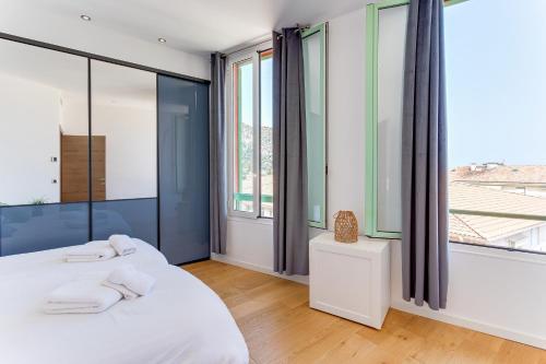 two beds in a room with large windows at 33 MARINONI AP4438 by Riviera Holiday Homes in Beaulieu-sur-Mer