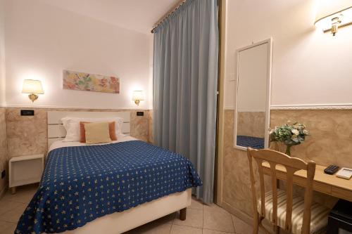 a bedroom with a bed and a desk and a mirror at Hotel Ascot in Rome