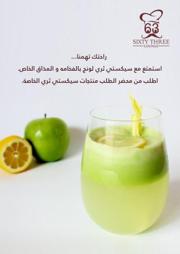 a drink in a glass next to an apple and a lemon at SIXTY THREE HOTEL SUiTES in Riyadh