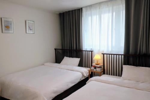 a hotel room with two beds and a window at Stay Hyuga Suwon in Suwon