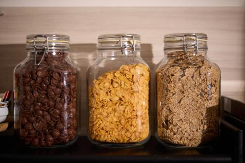 Cuatro frascos de vidrio llenos de diferentes tipos de frutos secos y semillas. en Hotel Vigo Plaza, en Vigo