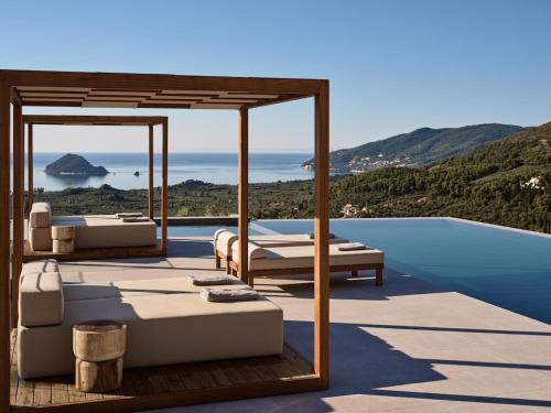 a patio with beds and a swimming pool at Marisia Luxury Villa, An Acre of Endless Blue in Lithakia
