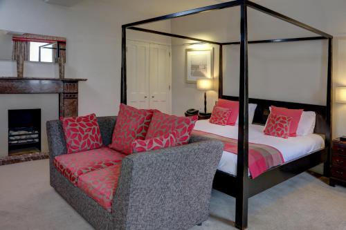 a bedroom with a four poster bed and a couch at Best Western Plus Angel Hotel in Chippenham