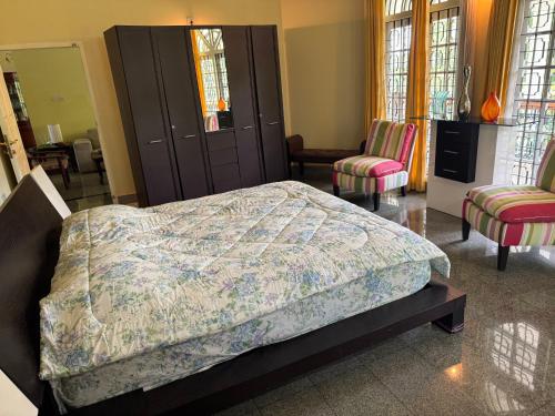 a bedroom with a bed and two chairs at FOURWINDS Bungalow in Kozhikode