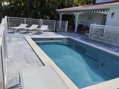 Una piscina con sillas al lado de una casa. en Villa de la Marina avec vue sur la mer et la montagne, en Gourbeyre