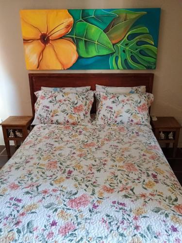 a bed with a floral comforter and pillows at Apto Centro de Búzios - 2 Quartos - Ar-condicionado in Búzios