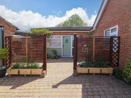 a garden with two wooden fences and a house at Rainbow's End in Swanton Morley