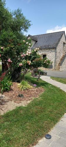 a house with a flowering tree and a sidewalk at Les Portes de l'Olivier in Grez-Neuville