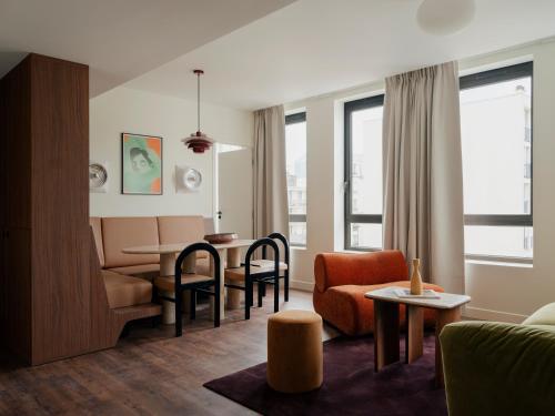 a living room with a couch and a table and chairs at Edgar Suites Levallois - Anatole France in Levallois-Perret