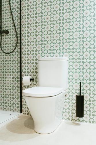a white toilet in a bathroom with wallpaper at Hostal Ainhoa in Tafalla