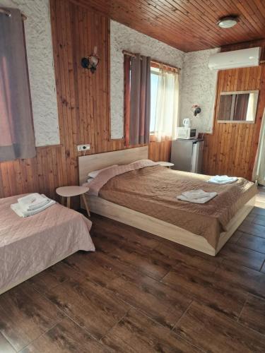two beds in a bedroom with wooden walls and wood floors at FAMILY HOTEL SAINT PETER in St. St. Constantine and Helena