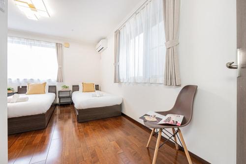 una stanza d'albergo con due letti e una sedia di Fukuei Stay Premium a Tokyo