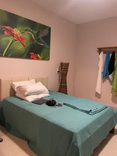 a bedroom with a bed with a painting on the wall at Suítes Sacai - Privacidade e Conforto in Conceição da Barra