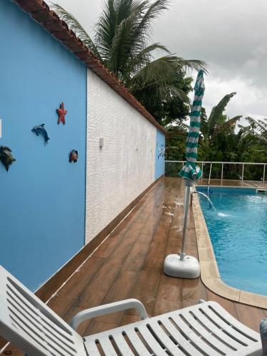 a pool with a slide and two chairs next to a building at Suítes Sacai - Privacidade e Conforto in Conceição da Barra