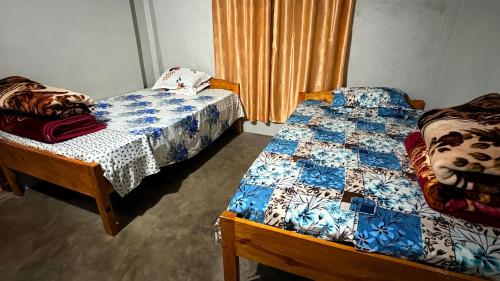 a bedroom with two beds and a window with curtains at John Myrthong Homestay 