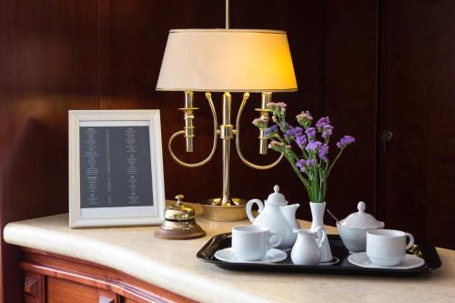 a table with a lamp and a plate with cups and flowers at Alexios Hotel in Ioannina
