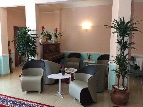 a waiting room with chairs and tables and plants at Hotel Erika in Caorle