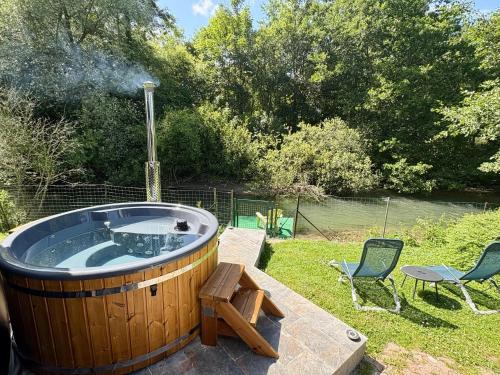 a hot tub in a yard with two chairs at Chalet convivial avec vue sur la rivière - 62 m² in Authuille