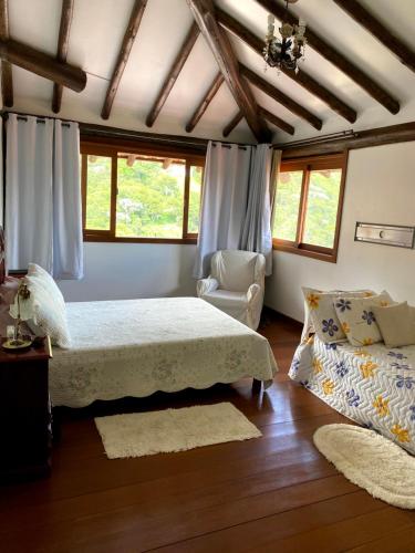 a bedroom with a bed and a chair and windows at Suíte em Condomínio de Luxo em Casa de Família in Araras Petropolis