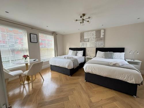 a bedroom with two beds and a table and chairs at The Grand Royal Kilburn House - 4BR/3BR w Parking in London