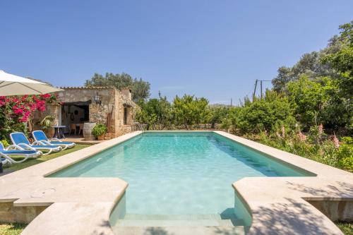 ein Swimmingpool in einem Hof mit Stühlen und Bäumen in der Unterkunft Villa Can Boseta by SunVillas Mallorca in Pollença