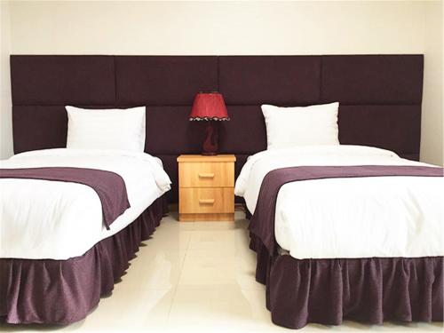 a bedroom with two beds and a red lamp on a night stand at J Hotel in Ulaanbaatar