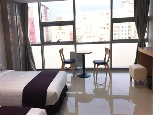 a bedroom with a bed and chairs and a large window at J Hotel in Ulaanbaatar