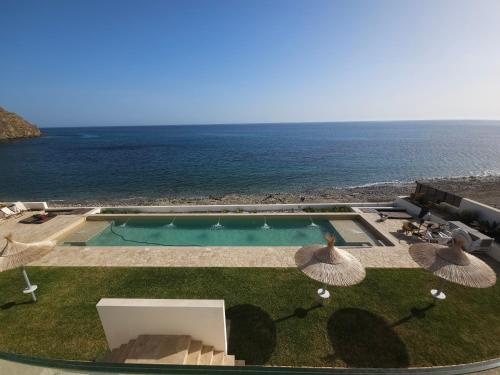 an outdoor swimming pool with umbrellas and the ocean at CasaCarbonito in Carboneras