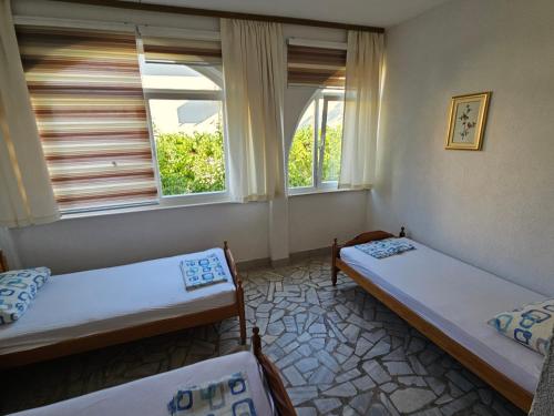 two beds in a room with two windows at Apartments Alma in Orebić