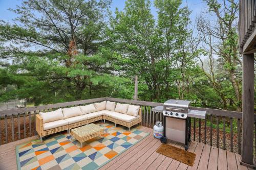 a patio with a couch and a grill on a deck at 4 Br Mtn Cabin Sauna Hot Tub Fire Pit Putt Putt in Albrightsville