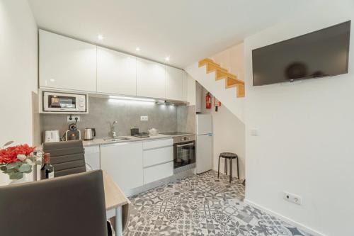 BicasにあるCedofeita Loft by Hostyの白いキャビネットとテーブルと椅子のあるキッチン