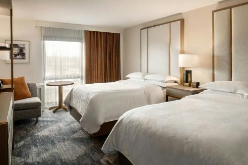 a hotel room with two beds and a chair at Madison Marriott South in Madison