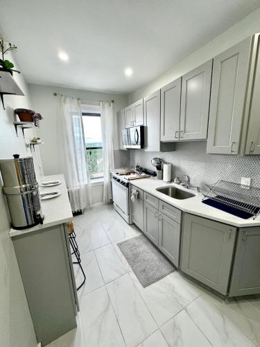 a kitchen with white cabinets and a large window at Sunny Jersey City 1BR, 25 min to NYC, 15min to EWR, King Bed, Hammock & Park Views in Jersey City