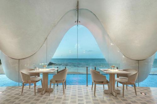 a restaurant with tables and chairs and a view of the ocean at La Concha Resort, Puerto Rico, Autograph Collection in San Juan