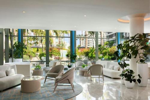 a lobby with white couches and chairs and plants at La Concha Resort, Puerto Rico, Autograph Collection in San Juan