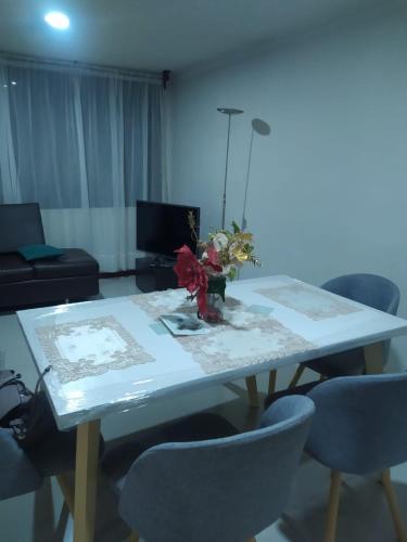 a table with chairs and a vase of flowers on it at Apartamento acogedor Duitama in Duitama