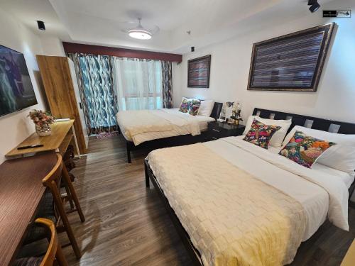 a hotel room with two beds and a table and a desk at Lazuli Elegant Studio Condo Unit in Baguio