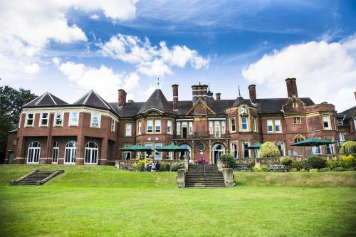 a large brick building with a grass yard in front at Moor Hall Hotel & Spa in Sutton Coldfield