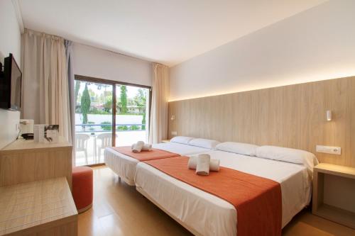 une chambre d'hôtel avec un grand lit et des serviettes. dans l'établissement Hotel Gran Garbi & AquaSplash, à Lloret de Mar