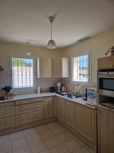 una cocina con armarios de madera y un fregadero en La combette, en Aubignan