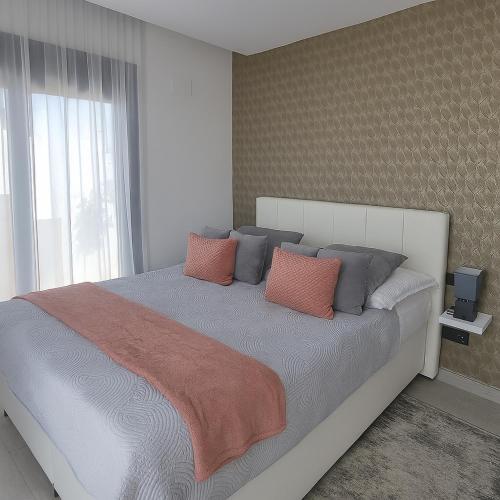 a bedroom with a large bed with orange and gray pillows at VILLA VERAMAR in Finestrat