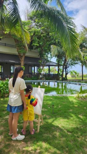 a woman and a child standing next to a painting at ZEN Resort - Villa beach- Garden in Xóm Tram