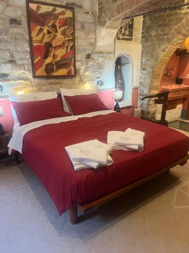 a bedroom with a large red bed with towels on it at Bed and Wine in Papiano