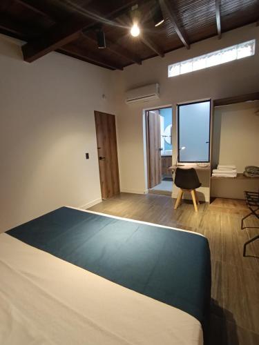 a room with a bed and a desk and windows at Bluelux Med - B&B in Medellín
