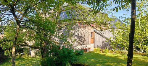 a large stone house with trees in front of it at L'Eaubergerine in Herbeumont