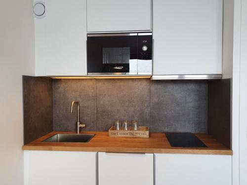 une cuisine avec un évier et un micro-ondes dans l'établissement Charmant 2P rénové, accès skis aux pieds, Méribel - FR-1-182-238, à Les Allues