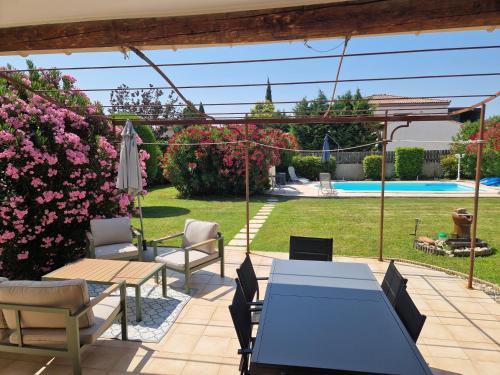 Un patio con mesa y sillas y flores. en La combette, en Aubignan