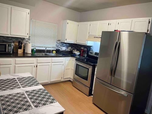 Una cocina con gabinetes blancos y un refrigerador de acero inoxidable. en Downtown 2BR Gem: Near Soaring Eagle & Downtown, en Mount Pleasant